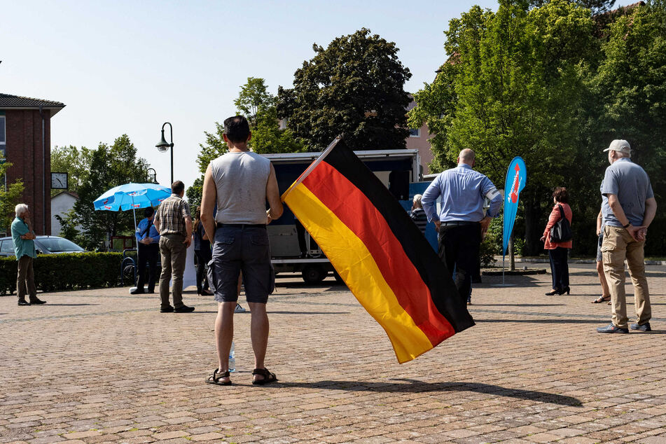 Einige Anhänger und Parteimitglieder der AfD Oder-Spree stehen auf dem Marktplatz der brandenburgischen Gemeinde Grünheide und protestieren gegen den geplanten Bau der Tesla-Fabrik.