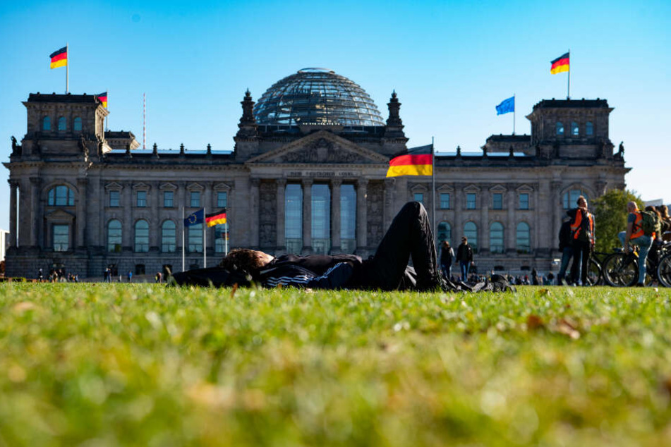 Eine Frau sonnt sich auf der Wiese vor dem Reichstag.