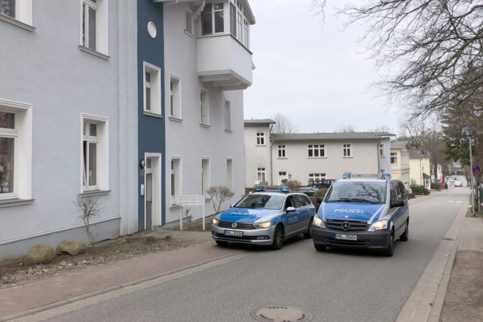 Einsatzfahrzeuge der Polizei stehen vor einem Wohnhaus, in dem eine junge Frau tot aufgefunden wurde.