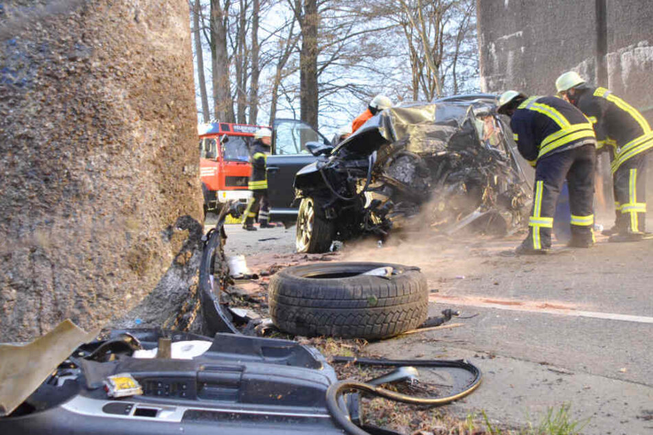 Einsatzkräfte stehen vor dem zerstörten Autowrack.
