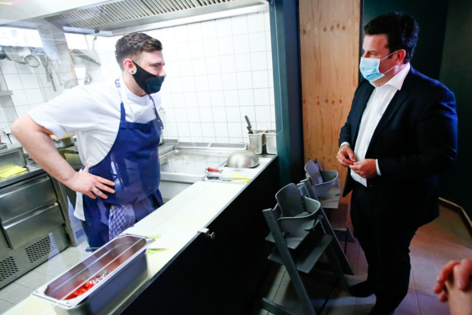 Bundesarbeitsminister Hubertus Heil (r - SPD) spricht mit einem Mitarbeiter im Restaurant "Funky Fish".