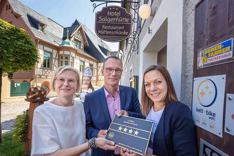 DEHOGA-Geschäftsführerin Franziska Luthardt (37) übergibt die Vier-Sterne-Plakette an die Hotel-Inhaber Brit (51) und Markus Gorny (50).