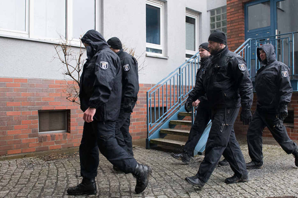 Polizisten gehen an einem Wohnhaus in Alt-Hohenschönhausen vorbei.