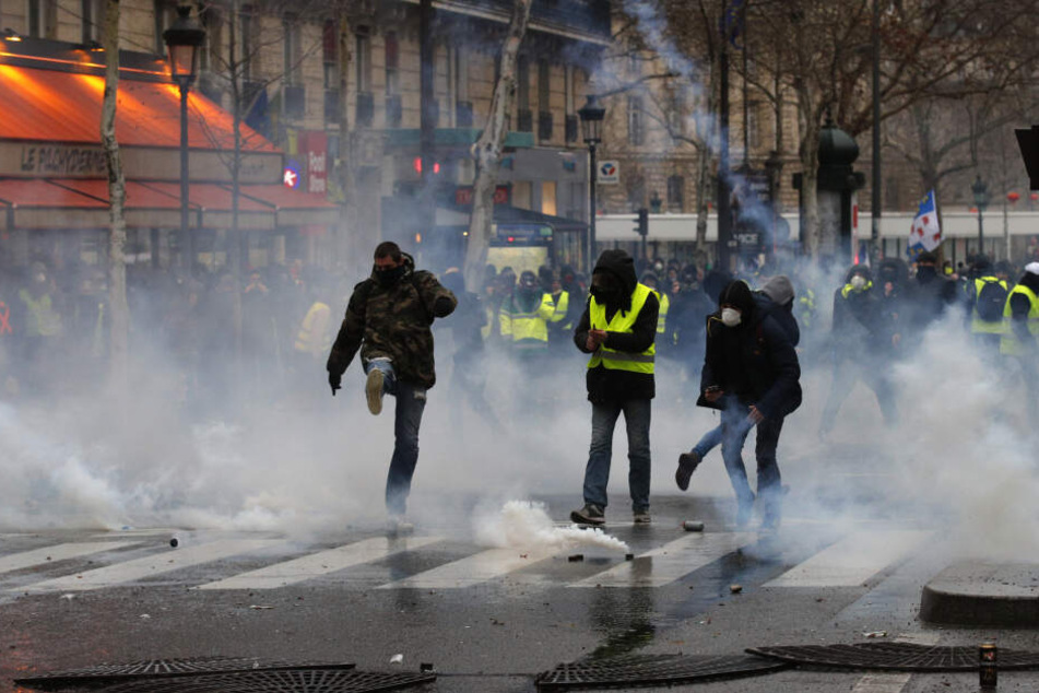 Demonstranten der "Gelben Westen" treten gegen Tränengasgranaten.