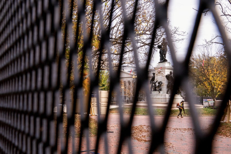 A worker walks near security fencing erected near the White House ahead of the 2024 presidential election.