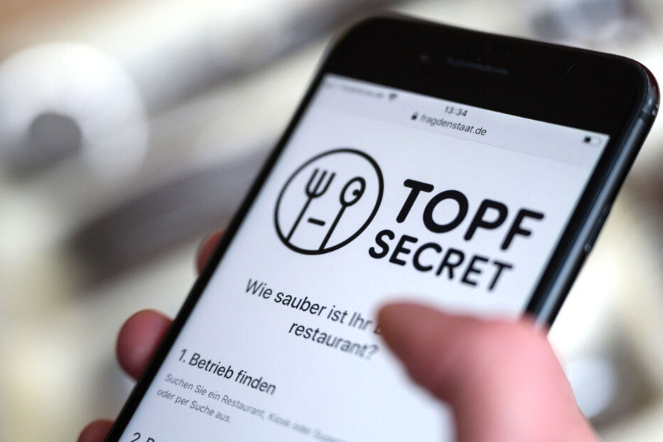 Eine Frau bedient auf ihrem Smartphone die Homepage "Topf Secret".