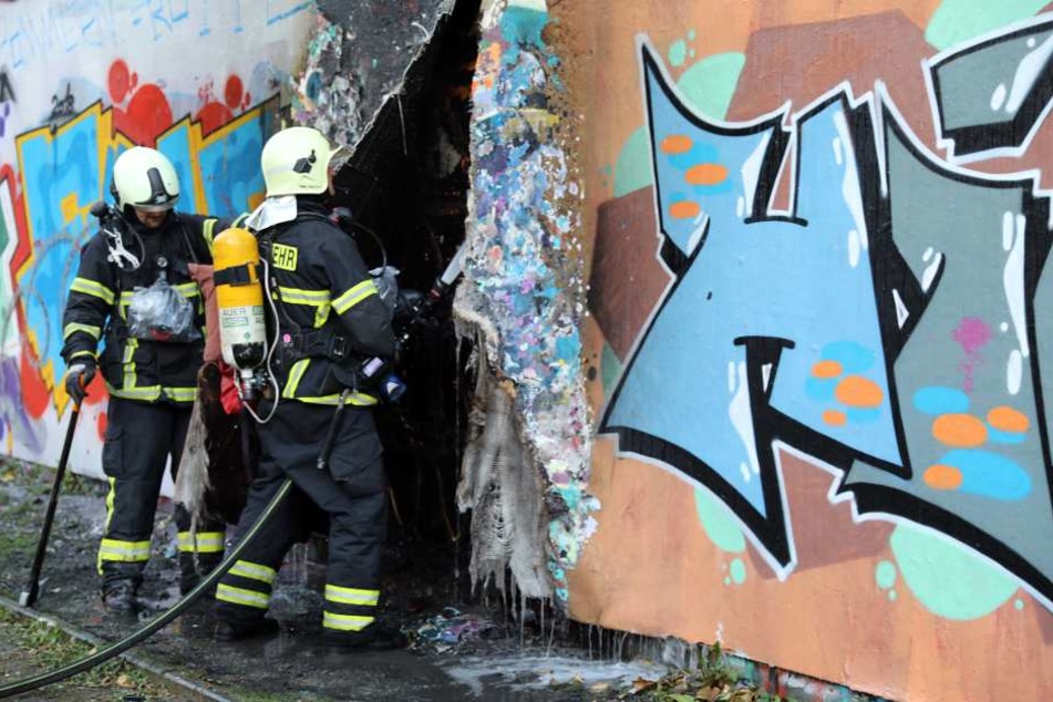 Einsatzkräfte der Feuerwehr löschen die restlichen Glutnester hinter der Fassade.