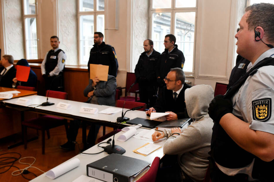 Der Angeklagte Vater (Mitte) wird mit seinen Söhnen beim Prozessauftakt von Justizwachtmeistern bewacht.