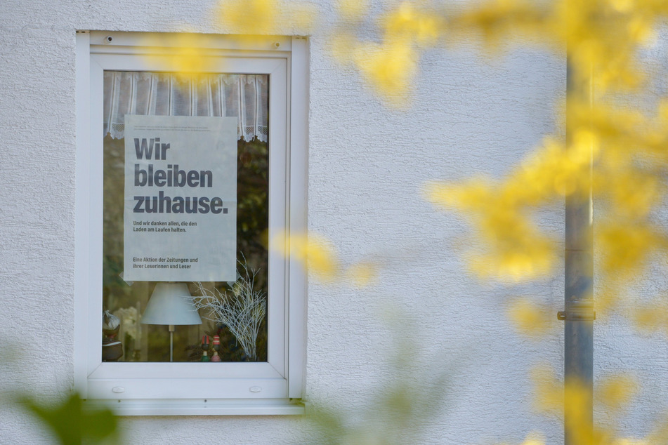 "Wir bleiben zuhause. Und wir danken allen, die den Laden am Laufen halten." steht auf einer Zeitungsseite, die in einem Fenster im Landkreis Leipzig hängt.