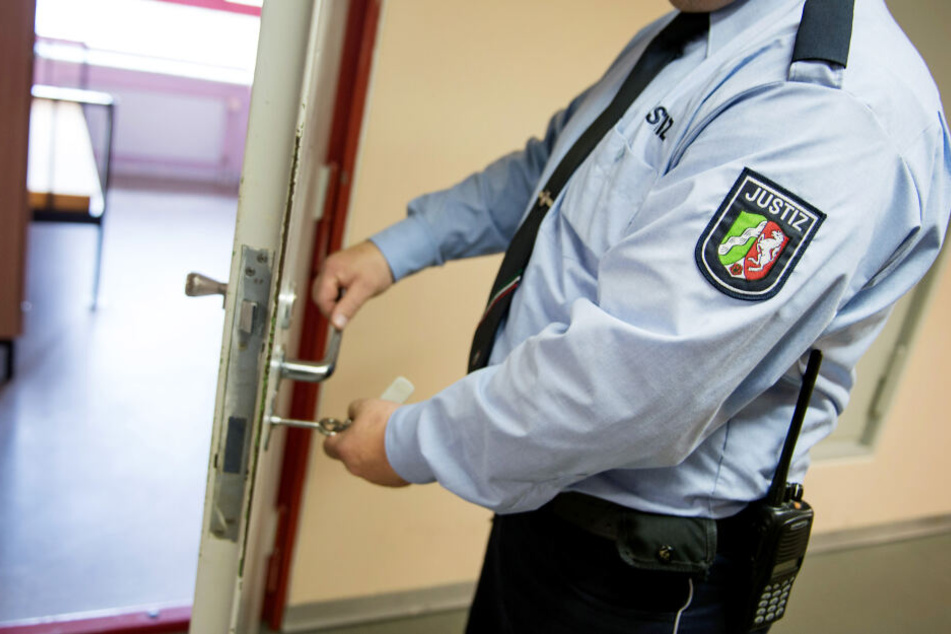 Ein Justizvollzugsbeamter schließt in der Justizvollzugsanstalt eine Tür.