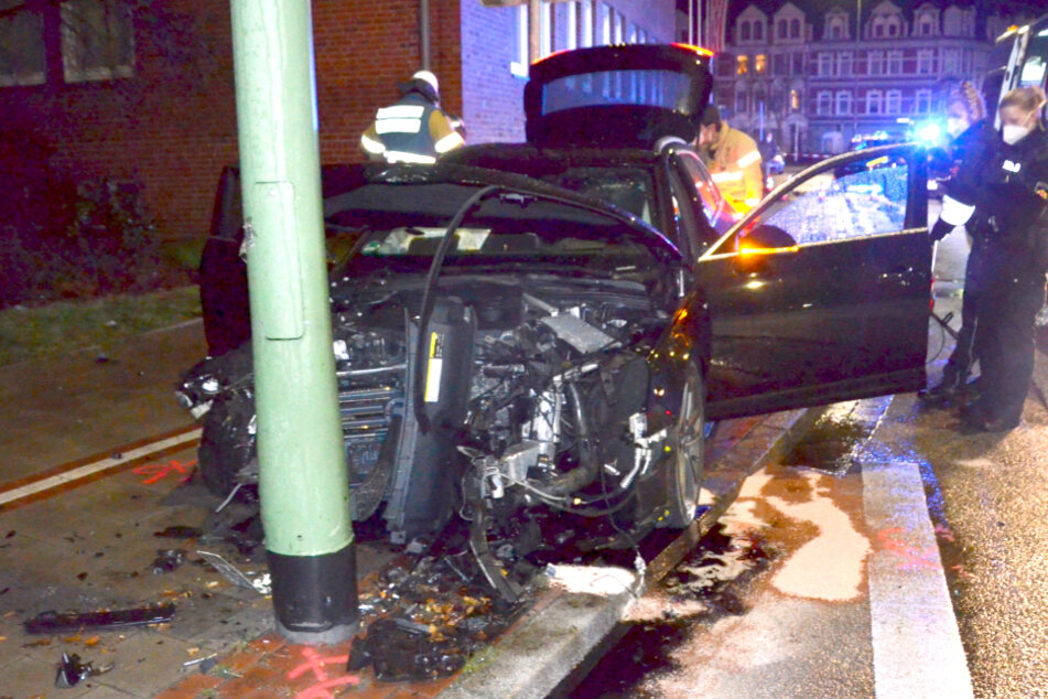 Einsatzkräfte stehen neben dem verunfallten Wagen.