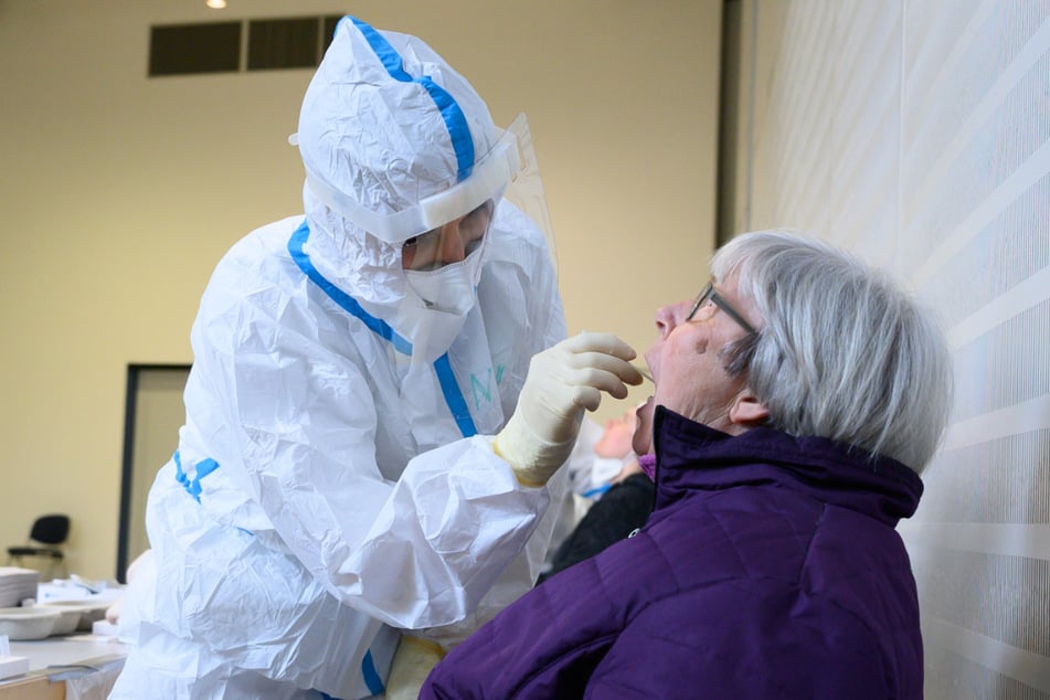 Eine Seniorin sitzt während eines Corona-Massentests in der Veranstaltungshalle vor einer Mitarbeiterin vom Gesundheitsamt. Wegen hohen Infektionszahlen sollen am Mittwoch Massentests im Wartburgkreis starten.