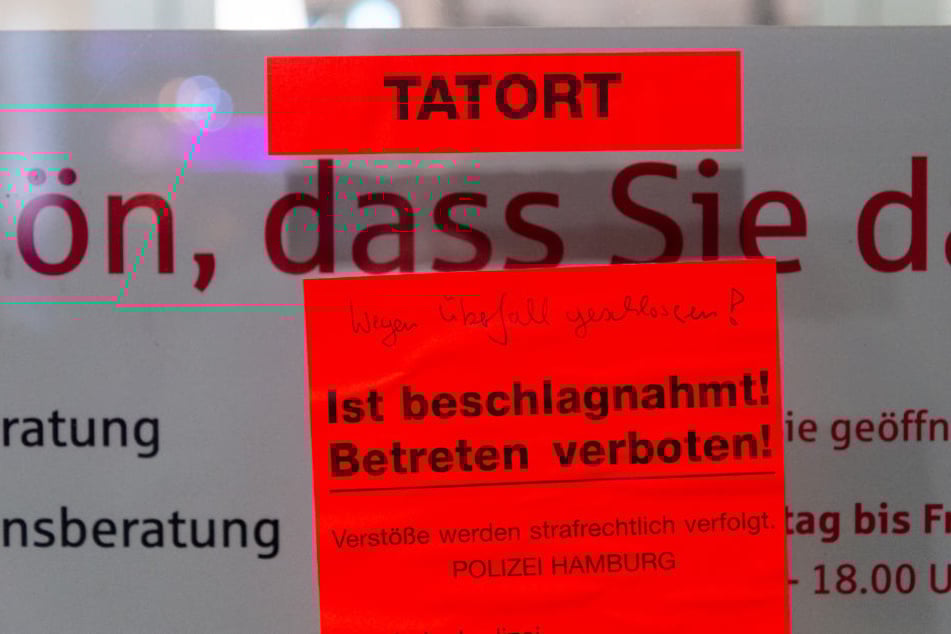 An der Tür der Bankfiliale klebt ein großer Zettel, der auf den Tatort hinweist.