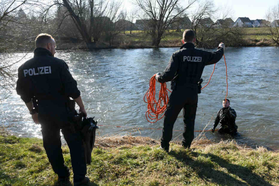 Polizeikräfte unterstützen einen Taucher, der den Uferbereich absucht.