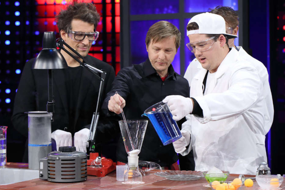 Daniel Hartwich (l.) beobachtet, wie Chris Tall (r.) Dr. Marc Sacher bei einem Experiment mit Superabsorbern hilft.