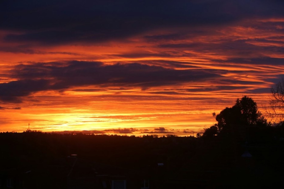 Grund für den roten Himmel sind feuchte Luftmassen und eine leichte Wolkendecke, die schon vor dem Aufgang der Sonne angestrahlt wurde.