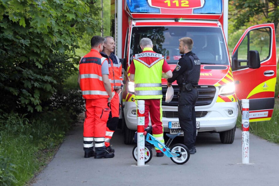 Einsatzkräfte von Polizei und Rettungsdienst stehen am Samstag in einem Park in Rostock-Lütten Klein.