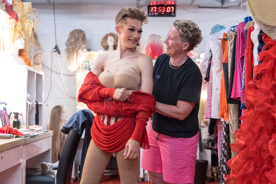 Mama Joana hilft in der Garderobe ihrem Sohn Moritz ins rote Kostüm.
