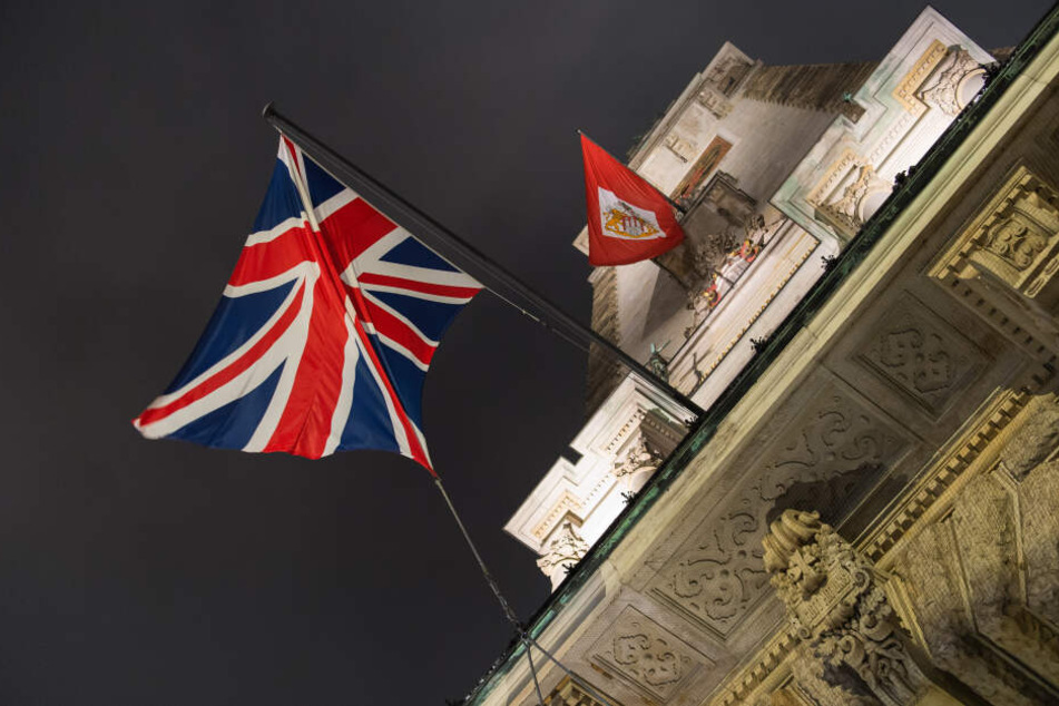 Eine britische Flagge hängt neben einee Fahne mit dem Wappen von Hamburg am Rathaus der Hansestadt.