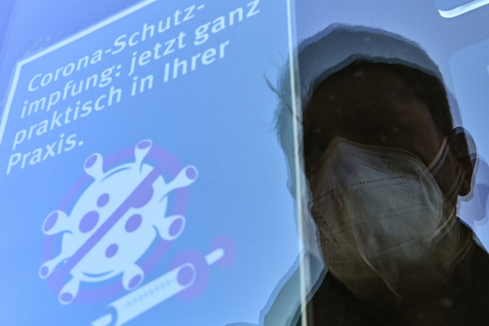 Ein Zettel mit der Aufschrift "Corona-Schutzimpfung: jetzt ganz praktisch in Ihrer Praxis" hängt an einer Scheibe zum Eingang einer Hausarztpraxis.