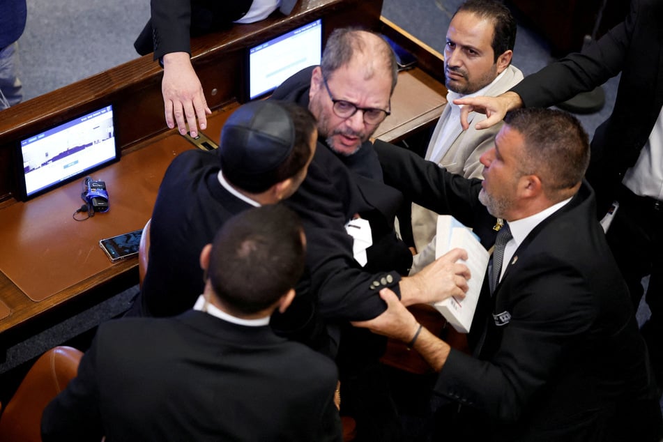 Knesset member Ofer Cassif is removed from the hall after raising a sign during Donald Trump's address on October 13, 2025.