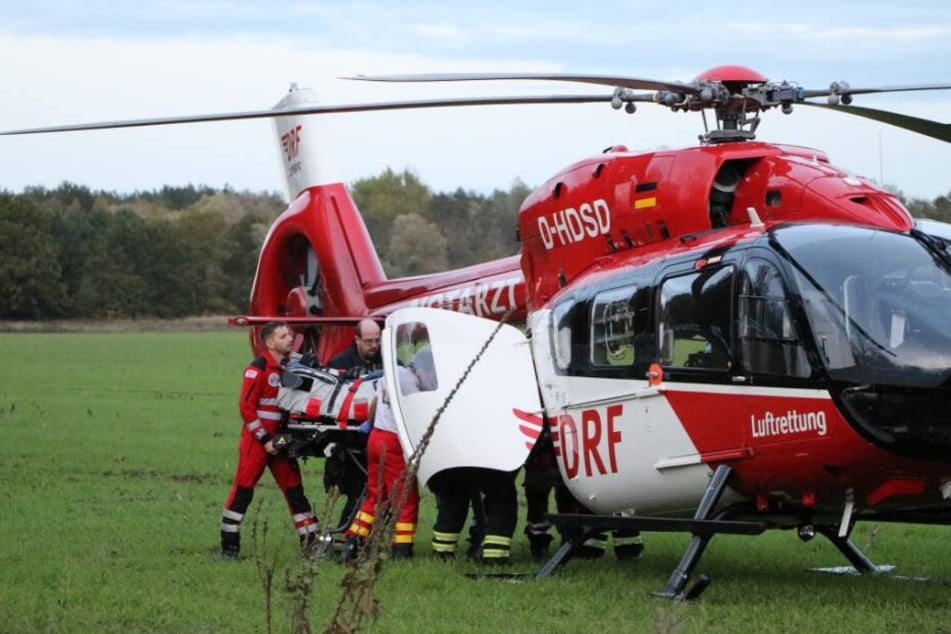 Rettungskräfte heben ein Unfallopfer auf einem Feld in einen Rettungshubschrauber. (Archivbild)