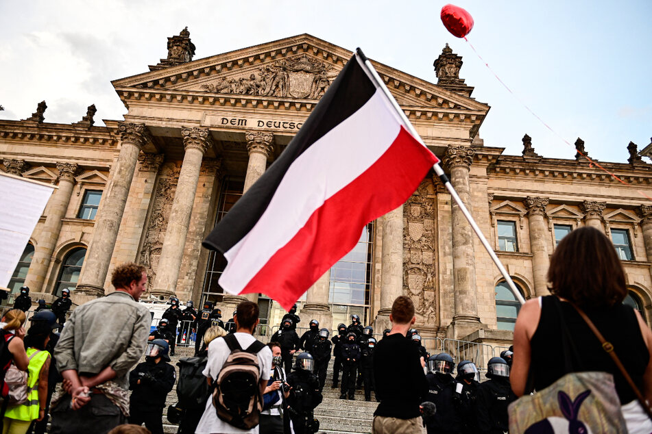 Berlin, 29. August 2020: Teilnehmer einer Kundgebung gegen die Corona-Maßnahmen stehen vor dem Reichstag, ein Teilnehmer hält eine Reichsflagge.