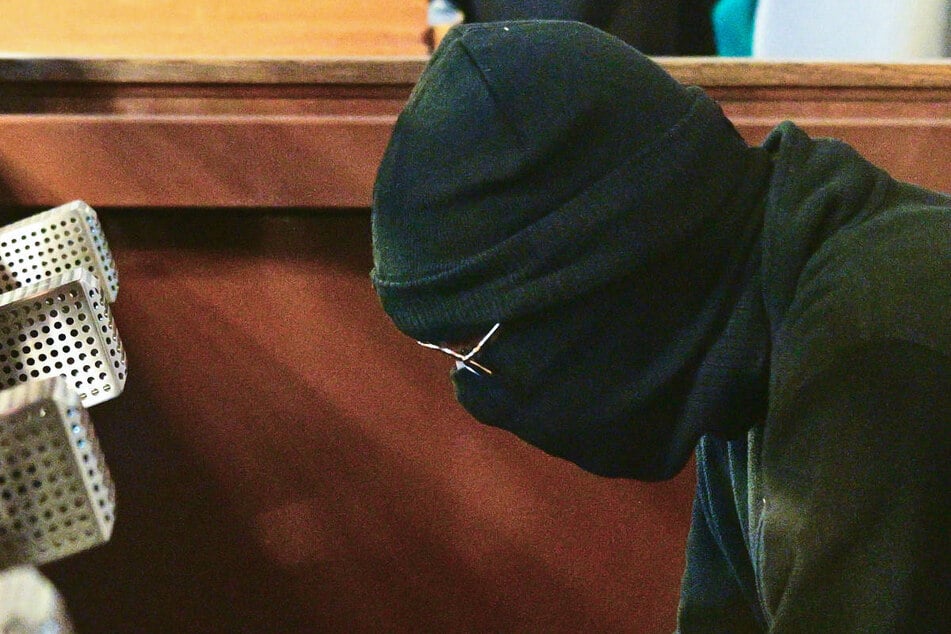 Der Verurteilte sitzt während des Prozesses verhüllt und mit Sonnenbrille auf der Anklagebank.