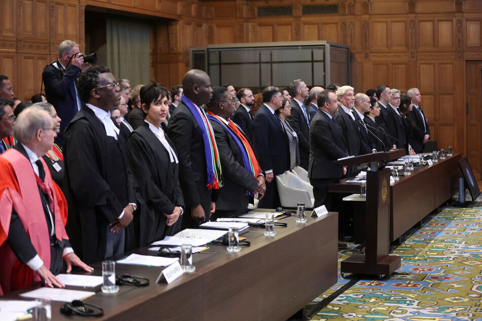 South Africa's Minister of Justice Ronald Lamola, lawyer Adela Hassim, and the delegation stand as judges at the International Court of Justice hear their request for emergency measures to stop Israel's genocidal acts in Gaza.