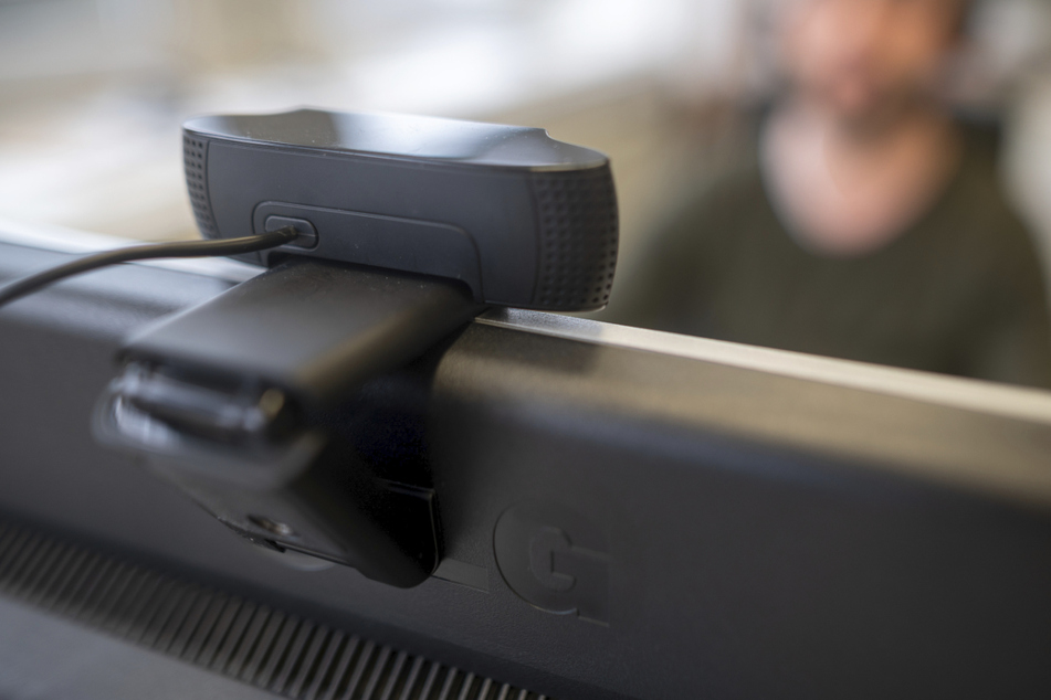 Ein junger Mann nimmt an einer Videokonferenz teil. Technische Tools sollen Studenten in Prüfungssituationen kontrollieren. (Symbolbild)
