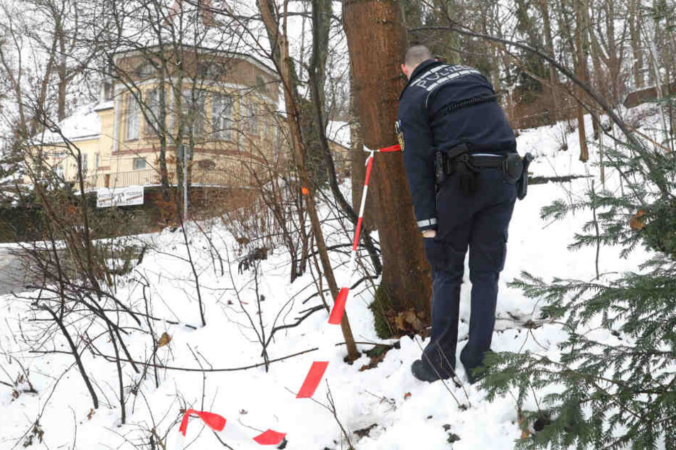 Ein Polizist entfernt Absperrband am Tatort im Bereich des Gigelbergs.