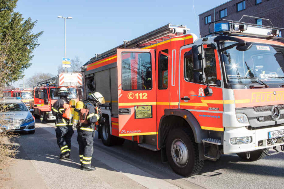 Feuerwehrleute prüfen an einem Einsatzfahrzeug ihre Ausrüstung, nachdem sie einen Brand gelöscht haben.