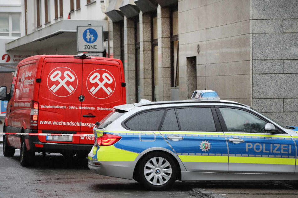 Ein Streifenwagen der Polizei steht vor einem Geldtransporter in Solingen.