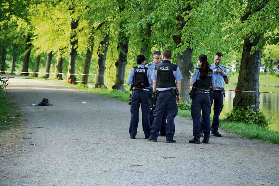 Mordversuch im Park: Polizisten haben den Tatort für die Spurensicherung abgesperrt. Die Tasche des Opfers liegt noch auf dem Asphalt.