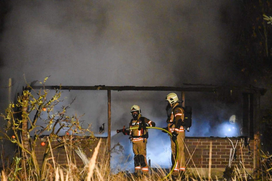Feuerwehrmänner vor der völlig niedergebrannten Gartenlaube.