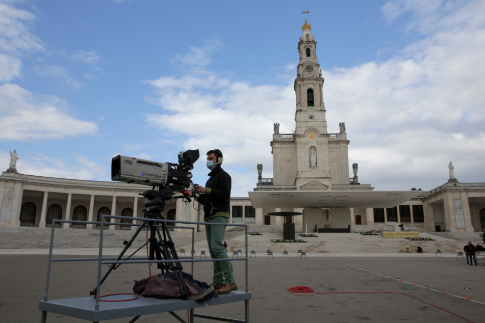 Portugal: Ein Kameramann richtet seine Kamera mit der Kathedrale von Fatima im Hintergrund vor dem Beginn der Feierlichkeiten am katholischen Wallfahrtsort ein.
