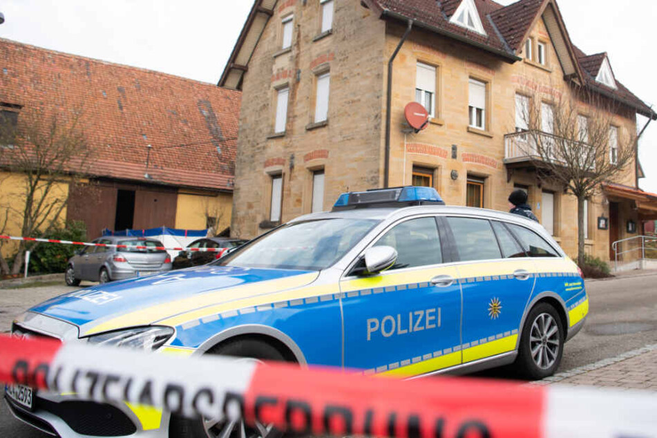Am Tag nach der Tat steht ein Polizeiauto vor dem Haus hinter Absperrband.