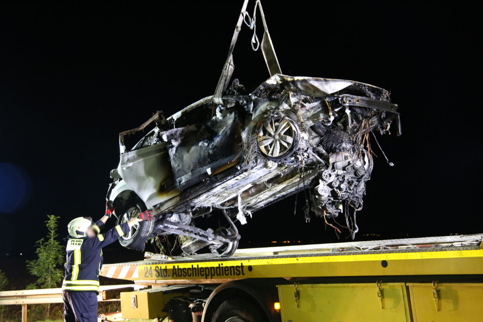 Das kaputte und verbrannte Auto wird auf die Ladefläche eines Abschleppdienstes geladen.