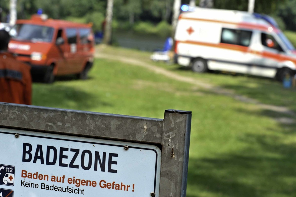 Rettungsautos stehen nach einem Badeunfall an einem See.