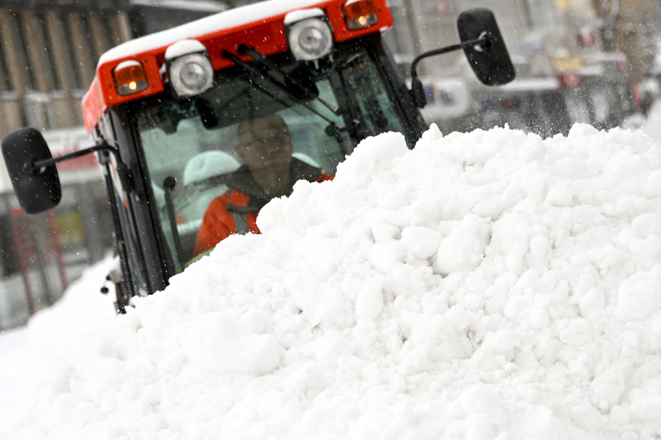 Ein Mann in einem Räumfahrzeug türmt Schneemassen in Kassel auf einen Haufen.