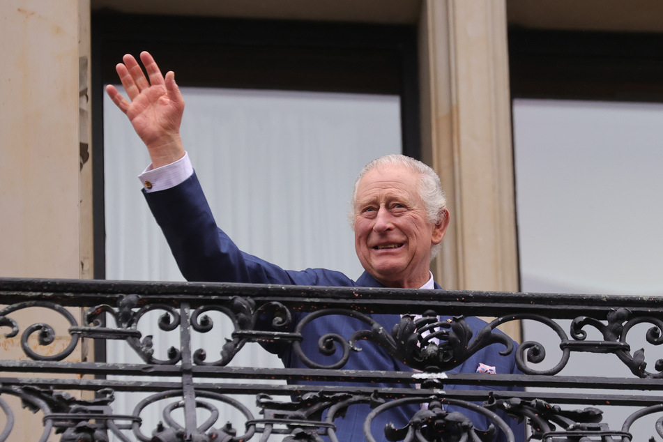 König Charles III. von Großbritannien winkt auf dem Balkon vom Hamburger Rathaus.