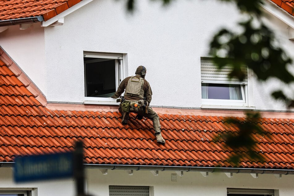 Ein Beamter des SEK ist auf einem Vordach eines Wohnhauses im Rahmen einer Zwangsvollstreckung im Einsatz.