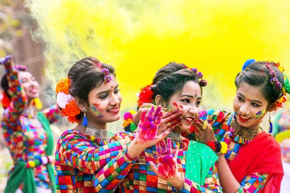 Drei Teilnehmerinnen der Feierlichkeiten zum Holi-Fest in Nadia (Indien) reiben sich gegenseitig Farbpulver in die Gesichter.