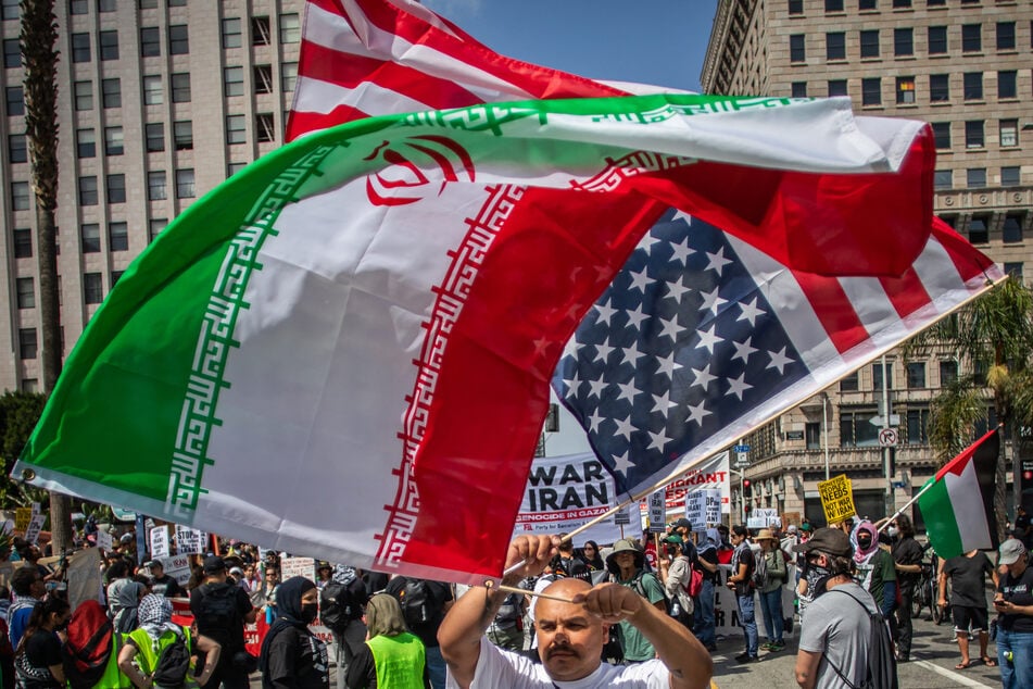 A protester holds an Iranian flag and an upside-down American flag during a demonstration in Los Angeles, California, on June 21, 2025.