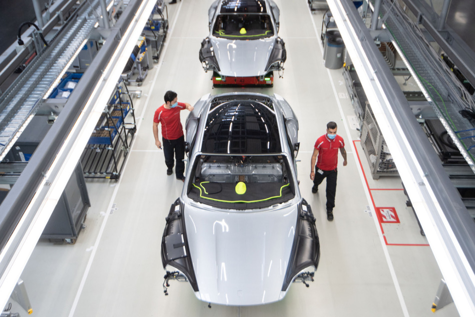 Stuttgart: Mitarbeiter der Porsche AG haben in der Produktion des batterieelektrische angetriebenen Sportwagens Porsche Taycan einen Mund-Nasen-Schutz an.