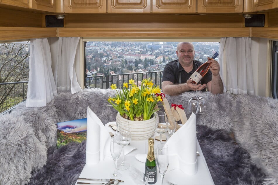 Wirt Marco Stelter (41) reicht eine Flasche Rosé in den Wohnwagen, der gemütlich eingedeckt ist.
