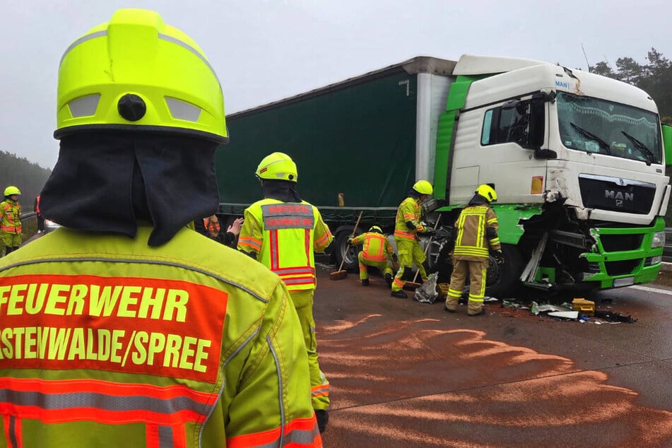 Feuerwehrleute sichern einen der beschädigten Sattelschlepper an der Unfallstelle ab.
