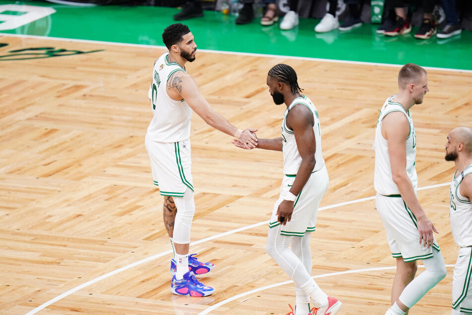 Boston Celtics guard Jaylen Brown (c.) and forward Jayson Tatum (l.) high five during game one of the 2024 NBA Finals against the Dallas Mavericks.