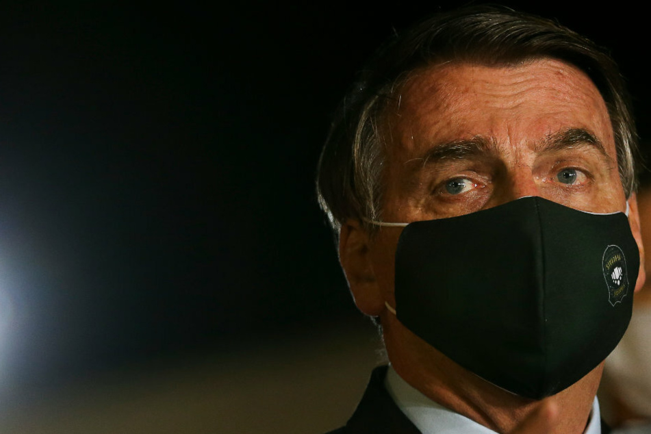 Jair Bolsonaro, Präsident von Brasilien, spricht mit schwarzem Mundschutz vor Journalisten im Regierungspalast.