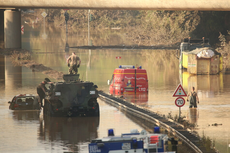 Ein Panzer der Bundeswehr zog am Sonntag einem Wagen aus der Flut. Ein Einsatzwagen der Feuerwehr und ein LKW stehen noch unter Wasser auf der B265.